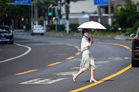 Nainen suojautui sateenvarjolla auringolta Shanghaissa.