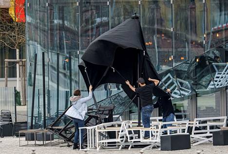 Ihmiset pitelivät terassin päivänvarjoa kovassa tuulessa Saksan pääkaupungissa Berliinissä torstaina 17. helmikuuta.