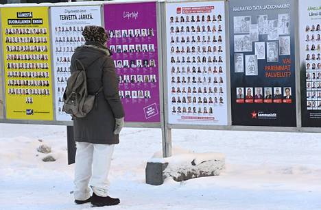Kansalainen tutki aluevaalimainoksia Espoon keskuksessa maanantaina.