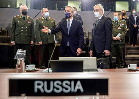 Naton pääsihteeri Jens Stoltenberg (kesk.) ohjasi Venäjän varaulkoministeriä Aleksandr Gruškoa neuvottelupaikalle Brysselissä keskiviikkona. Taustalla neuvotteludelegaatioiden sotilasedustajia.