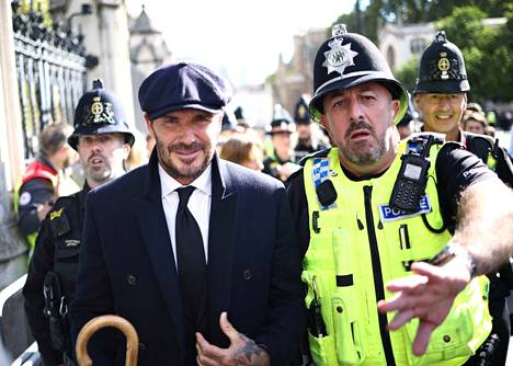 Entinen jalkapallotähti David Beckham poistumassa kuningattaren arkulta jonotettuaan Westminster Halliin yli 12 tuntia. Poliisi auttaa Beckhamia ihmismassan läpi.