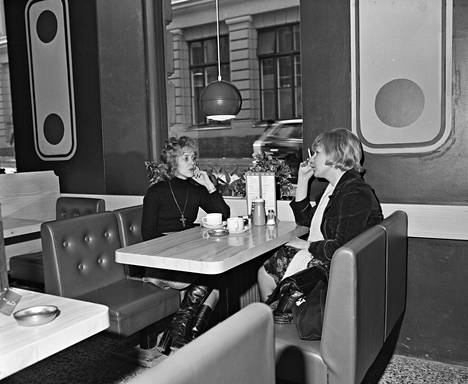 Kaksi asiakasta juo kahvia Bulevardi 6:ssa sijainneessa Wimpyssä, ja toinen tupakoi. Ikkunasta näkyy Yrjönkatu 18.