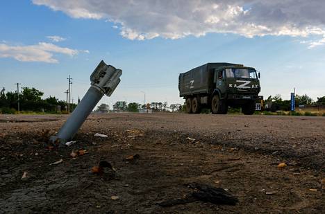 Venäläinen armeijan kuorma-auto ajaa räjähtämättömän ammuksen ohi Venäjän hallitsemassa Tšornobaivkan kylässä Ukrainassa 26. heinäkuuta 2022. 