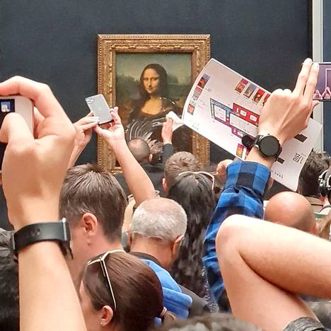 Ihmiset ottivat puhelimillaan kuvia, kun Mona Lisan suojalasia pyyhittiin puhtaaksi Louvressa sunnuntaina.
