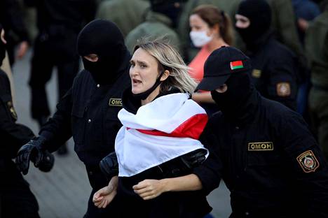 Kommandopipoiset poliisit ottivat mielenosoittajan kiinni lauantaina Minskissä.