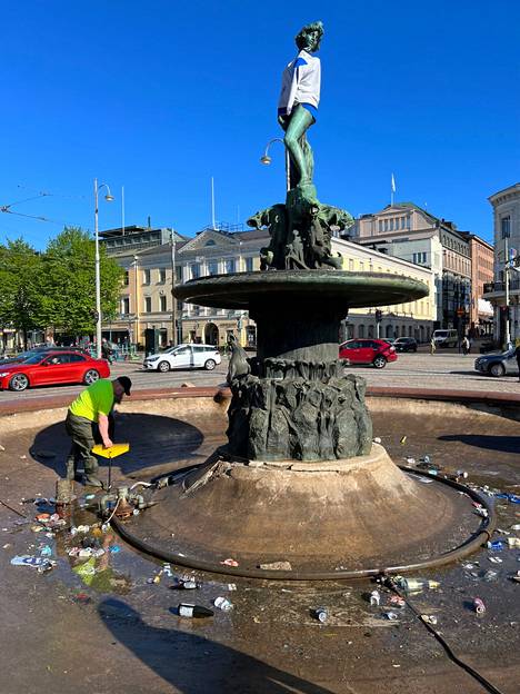 Staran puistotyöntekijä siivosi kultajuhlijoiden roskia Havis Amandan patsaalla Helsingissä maanantaina.