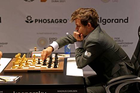 Magnus Carlsenilla on sääntöjen mukainen pukeutuminen: tumma puku ja valkea paita. Kuva on perinteisen šakin MM-turnauksesta joulukuulta.