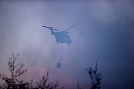 Puolustusvoimien helikopteri lensi savun läpi pudottamaan vettä Kalajoen suurelle maastopaloalueelle heinäkuussa 2021.