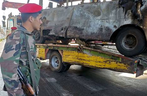 Syyrian turvallisuusjoukkojen sotilas vartio pommi-iskussa tuhoutunutta linja-autoa Damaskoksessa 20. lokakuuta.