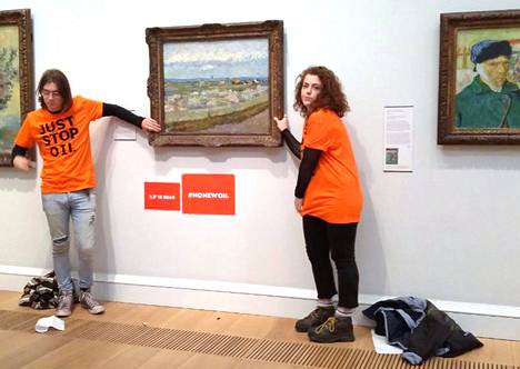 Louis McKechnie ja Emily Brocklebank liimasivat kätensä Vincent van Goghin Persikkapuut kukassa -maalauksen kehykseen Lontoossa.
