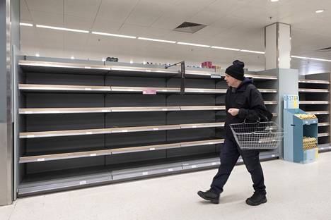 Mies kävelee tyhjien hyllyjen ohi supermarketissa Lontoossa 21. maaliskuuta 2020.