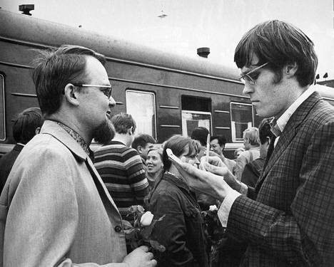 Jukka Rislakki (oik.) haastatteli juuri Kiinasta palannutta teatteriohjaaja Kalle Holmbergiä Helsingin rautatieasemalla vuonna 1971 – kirjan kuvitusta.