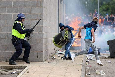 A rioter runs away from police in Rotherham on Sunday.