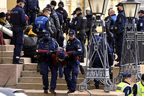 Poliisi kantoi mielenosoittajia pois Valtioneuvoston linnan edestä perjantaina.