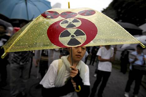 Ydinvoimaa vastustava mielenosoittaja piteli Tokyo Electric Power- yrityksen logon ja ydinvoiman logon yhdistävää printtisateenvarjoa sunnuntaina Tokiossa.