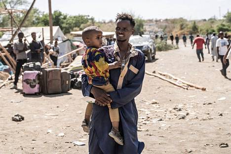 Sudanista Etiopiaan paennut mies kantoi lasta Metemassa 4. toukokuuta. Yhä useammat ovat lähteneet vaaralliselle matkalle päästäkseen turvaan Sudanista.