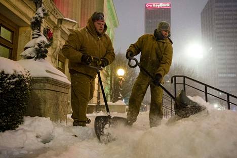 Luke Hannan ja Bryan Derr lapioivat lunta Ohion osavaltion parlamenttirakennuksen edessä Columbuksessa Yhdysvalloissa perjantaina.