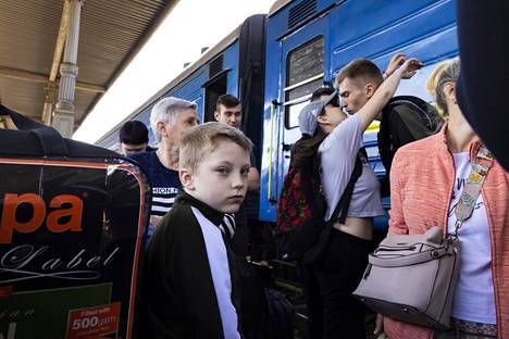 Eri matkaa Lvivin alueelta evakosta palanneet Anastasia Boršuk, 19, ja Vadim Kordjuk, 20, suutelevat Harkovan rautatieasemalla. Etualalla on Vadymin veljenpoika Maxim Kordjuk, 10. Perhe lähti pakoon taisteluita mutta on nyt palannut takaisin kotiin Harkovaan.