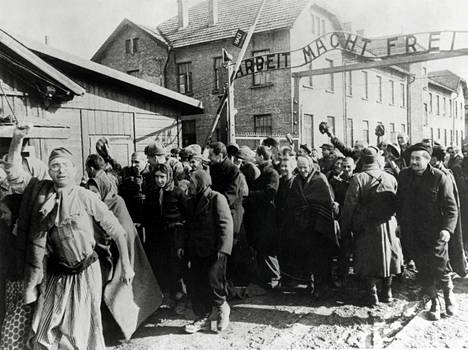 Auschwitz-Birkeaun tuhoamisleirin selviytyjiä poistumassa alueelta Arbeit macht frei, ”työ tekee vapaaksi” -kyltin alla helmikuussa 1945.