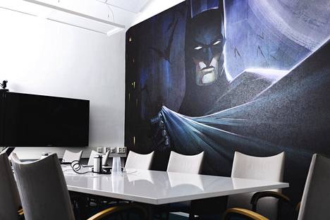 There is a large Batman-themed wallpaper on the wall of the conference room.