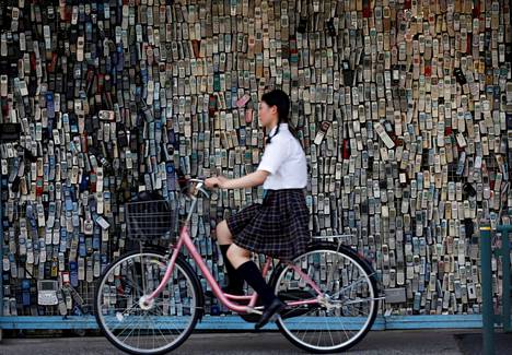 Koulupukuun pukeutunut japanilaistyttö pyöräili Tokiossa kesällä 2017.