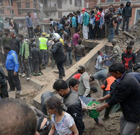 Nepalilaiset raivasivat romahtaneen rakennuksen palasia Kathmandun Durbarin aukiolla, joka on Unescon maailmanperintökohde.