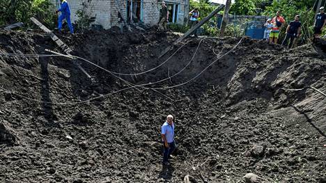 Mies seisoi Venäjän ohjusiskun tekemässä kuopassa Kushuhumissa Zaporižžjassa Ukrainassa keskiviikkona.