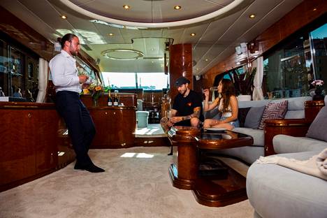 La Lux's Captain Stefano La Mela, Chef Samuel Suriano and Cruise Manager Virna Ribeiro de Oliveira hang out indoors while guests enjoy themselves on deck.  On a luxury yacht for rent, you can go for a spin with, for example, a champagne tasting, the price of which is 1,500 euros without drinks.