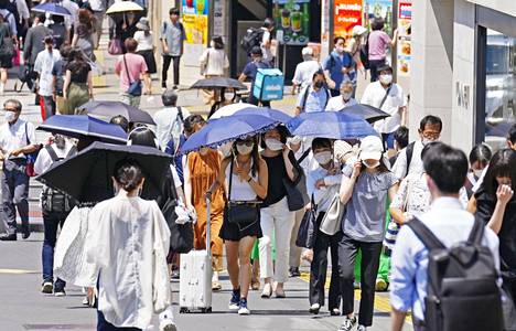 Japanilaiset yrittävät suojautua paahtavalta kuumuudelta aurinkovarjoin Tokion kaduilla. 