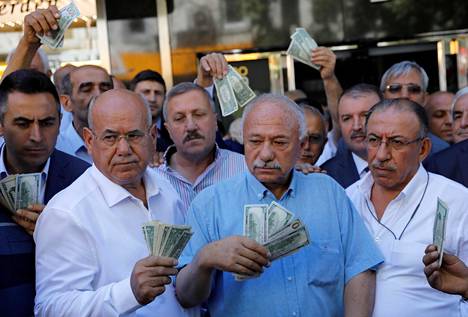 Yhdysvaltojen dollareita käsissään pitelevät liikemiehet poseerasivat valuutanvaihtotoimiston edessä Ankarassa vastauksena presidentti Recep Tayyip Erdoğanin vetoomukselle, jolla hän pyysi turkkilaisia myymään dollari- ja eurovaransa tukeakseen Turkin liiraa.