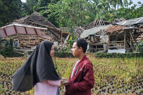 Locals stood in front of collapsed houses in Cianjur.