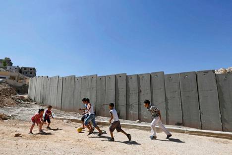 Palestiinalaislapset leikkivät lokakuussa Shuafatin pakolaisleirillä lähellä Jerusalemia. Taustalla on Israelin rakennuttama rajamuuri.