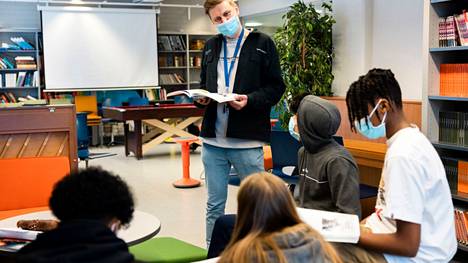Lukutaidon opettaja Aleksi Nissinen auttaa yhdeksäsluokkalaisia yhteiskuntaopin kirjaan perehtymisessä Itäkeskuksen peruskoulussa. 