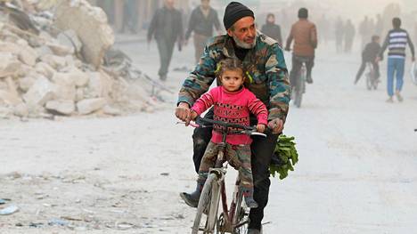 Mies ajoi polkupyörällä tyttärensä kanssa kapinallisalueella Itä-Aleppossa viime keskiviikkona.