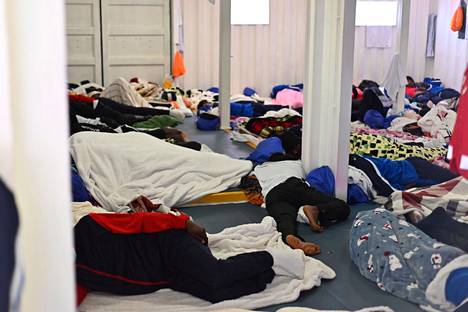 People sleeping on the floor of a ship.