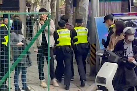Poliisit pidättivät ihmisen Wulumuqi- eli Ürümqi-kadulla Shanghaissa maanantaina. Ruutukaappaus videolta.