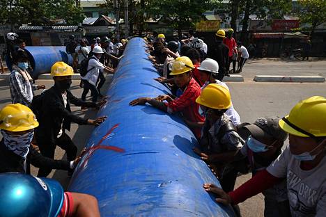 Mielenosoittajat rakensivat putkista barrikadia torstaina Yangonissa.