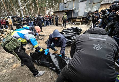 Poliisi ja kaupungin työntekijät laittoivat osittain palaneita ruumiita ruumispusseihin Butšassa tiistaina. 
