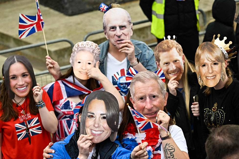 Kuninkaallisen perheen jäseniä esittäviin naamioihin pukeutuneita kruunajaisten seuraajia odottamassa kruunajaisten alkua.