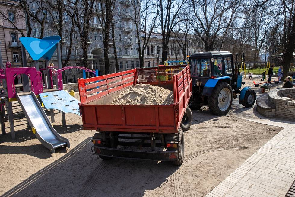 Kaupungin traktori toi leikkipuistoon lisää hiekkaa.