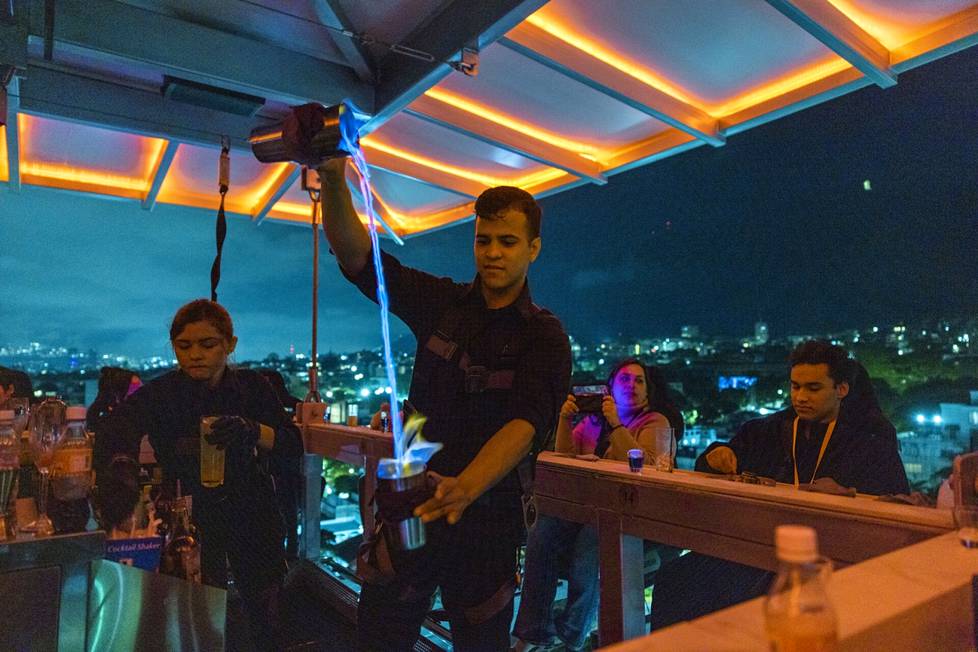 Baarimikko valmisti cocktailia Altum-ravintolassa, joka roikkuu nosturista Venezuelan pääkaupungin Caracasin yllä.