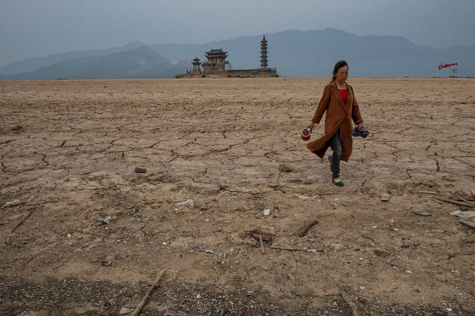 Nainen käveli kuivuneen Poyangjärven pohjalla. Taustalla kohoaa Luoxingdun-saari.
