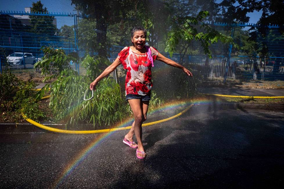 Kanadassa jatkuvat ennätyksellisen kovat helteet. Nainen vilvoitteli vesisuihkun alla Vancouverissa maanantaina. 