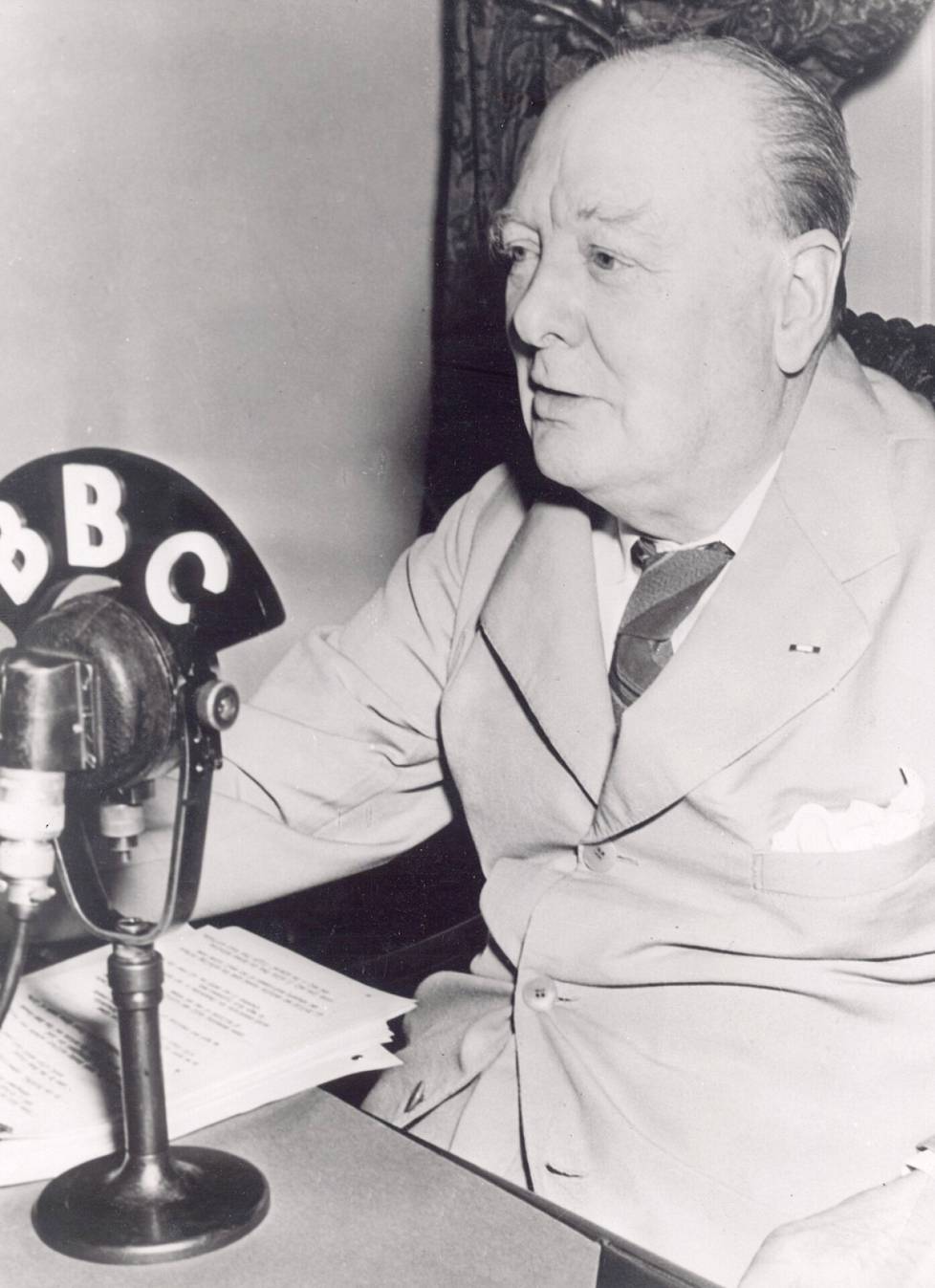 Former Prime Minister Winston Churchill speaks on BBC radio.  Churchill's tenure in the country ended in 1955. The BBC's television monopoly ended the same year.