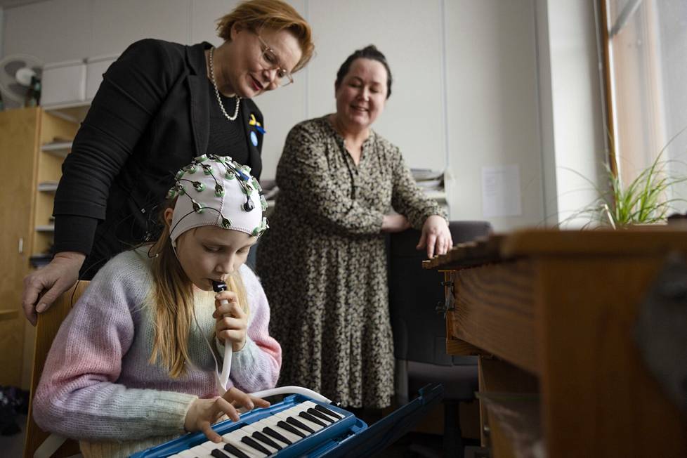 Helsingin yliopiston Minna Huotilainen (vas.) ja Mari Tervaniemi käyttävät aivosähkökäyrämittausta tutkiessaan, miten melodikan soittaminen vaikuttaa 9-vuotiaaseen Victoria Raitaan. 