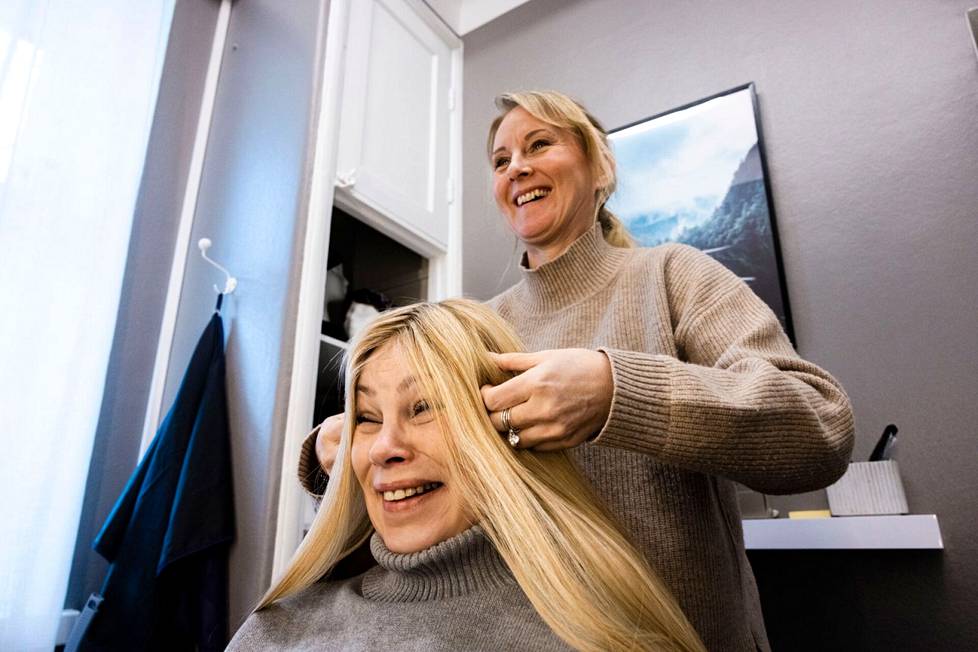 Niina Kursu asettelee peruukkia Anne Rautiaiselle. Nuorempana Rautiaisella oli vaaleat hiukset, mutta nyt väri ei enää tunnu omalta vaan lähinnä naurattaa.