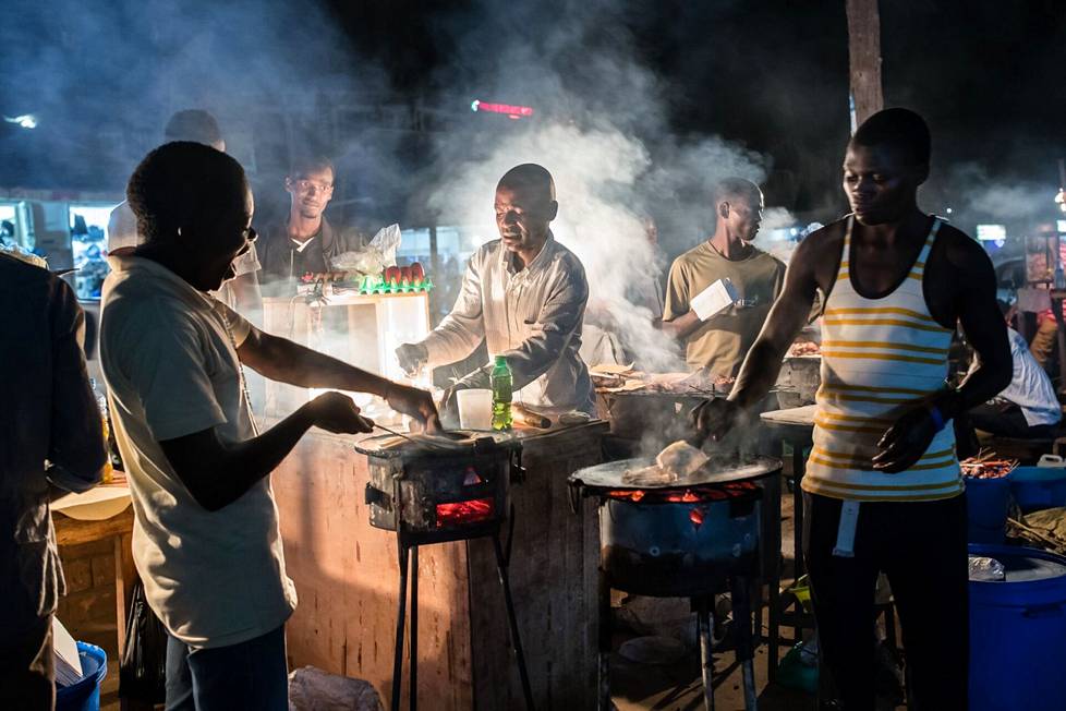 Anton Mussaka (center) and Bennet Waski shone on charcoal "rolexeja" ie pizzas made in the Ugandan capital, Kampala, in February 2018. 