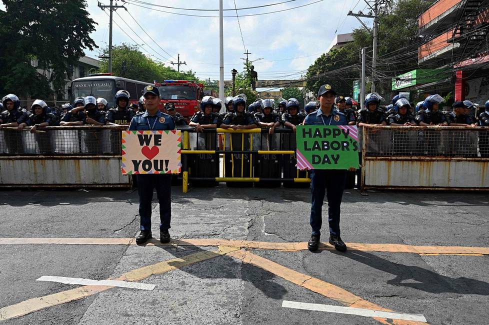 Mielenosoituksen valvontaan valmistautuvat poliisit osoittivat kylteillään tukea marssijoille Manilassa Filippiineillä.