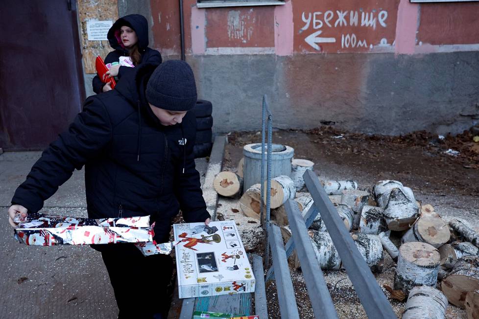 11-vuotias Volodymyr seisoo äitinsä vieressä avatessaan joululahjaansa, 4. tammikuuta Bahmutissa.