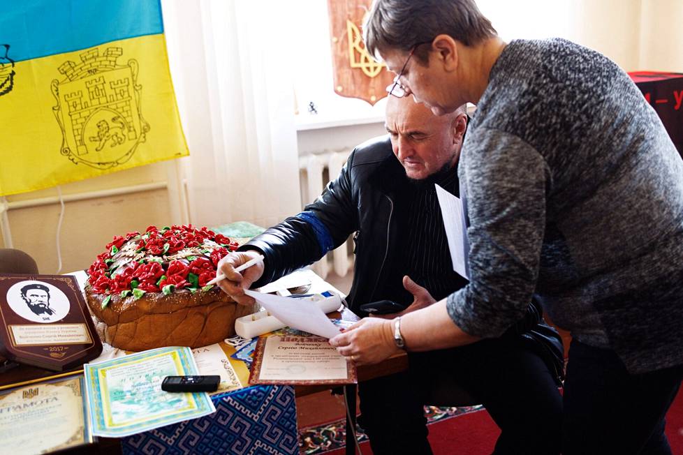 Osuustilan johtaja Serhi Voitšenko allekirjoittaa papereita toimistossaan.